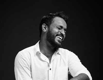 Black-and-white portrait of Bhagya laughing candidly against a dark studio background, paired with a bold magenta title card reading 'Bhagya – The Spreadsheet Samurai'.
