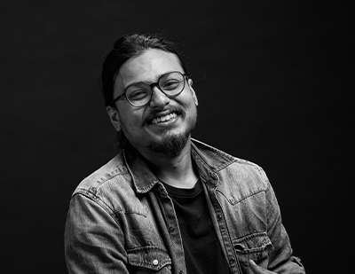 Black-and-white studio portrait of Deep smiling casually against a dark background, paired with a bold graphic slide reading 'DEEP – Man of Many Hats'.