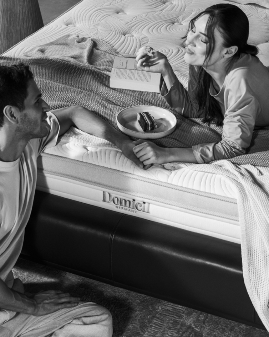 Domicil Sleep lifestyle brand communication visual featuring a couple on a premium mattress