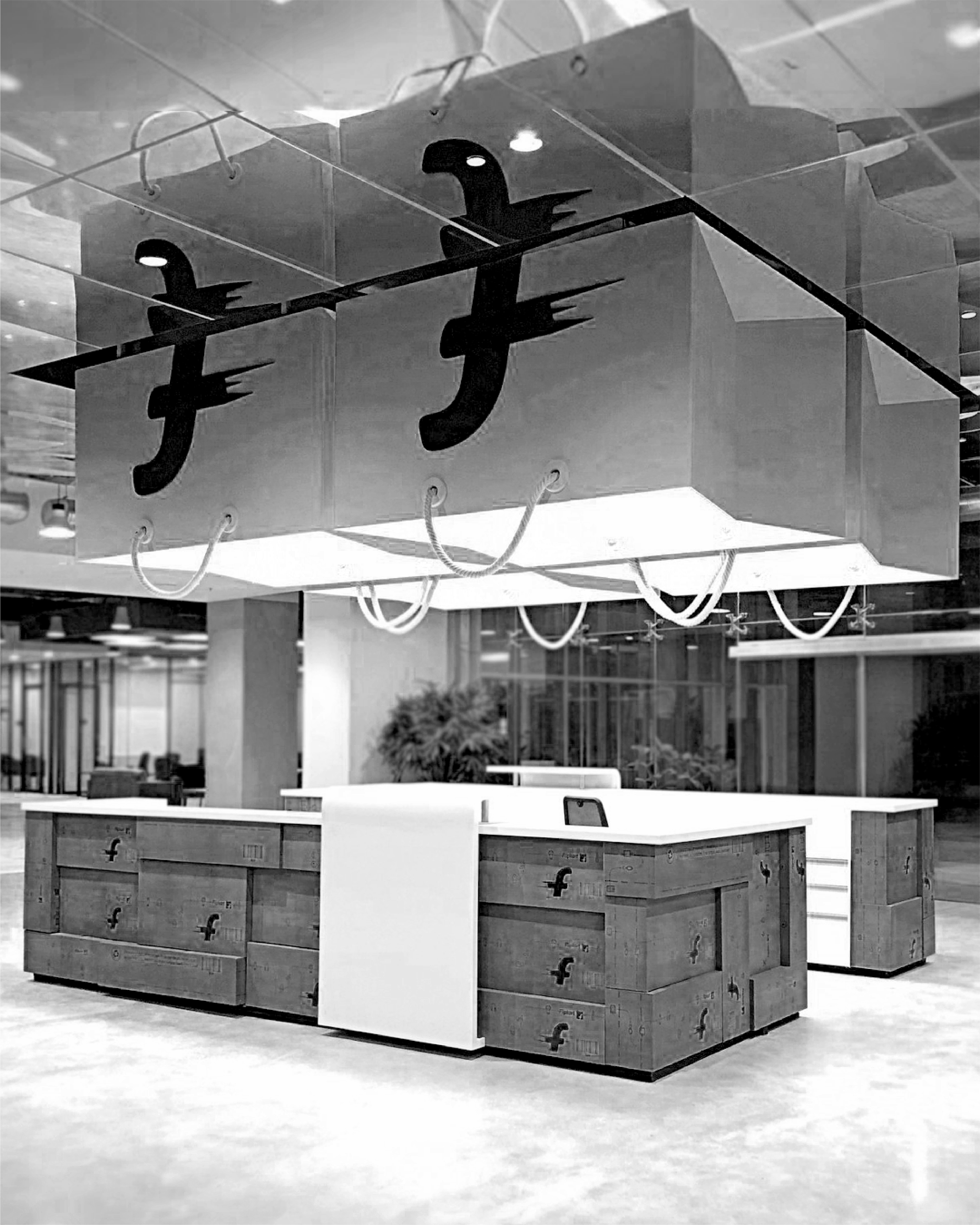 Flipkart office space interior design by JUMPINGGOOSE featuring a central desk and suspended branded forms for contemporary office design.