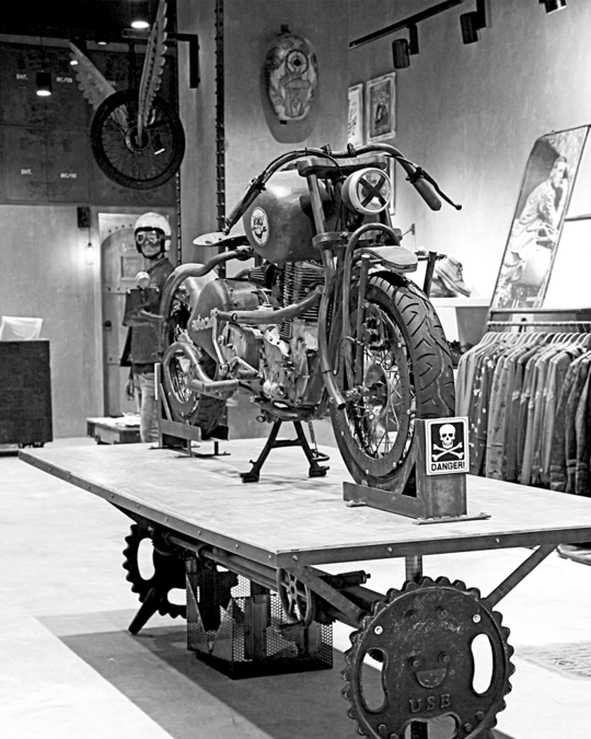 Motocult retail identity design by JUMPINGGOOSE using an industrial motorcycle setup to express visual identity guidelines.